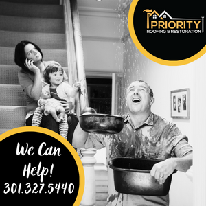 Mom and baby sitting on stairs calling Priority for help while Dad is standing under roof leak.